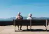man and woman sitting on bench facing sea
