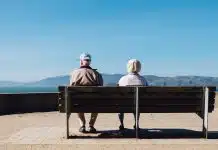 man and woman sitting on bench facing sea