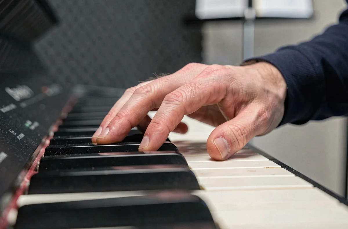 Gros plan réaliste d'une main d'homme sur les touches de piano mettant en valeur la touche noire si bémol