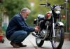 Entretien et maintenance du moteur Dax 125cc : conseils avisés Homme en chemise de travail vérifiant une moto Dax