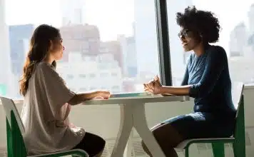 two women sitting beside table and talking