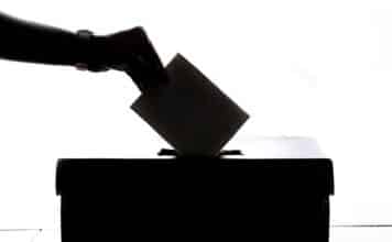 a person is casting a vote into a box